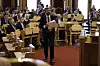 Jan Christian Vestre går med dokumentmappe mellom benkeradene i Stortinget under debatt.