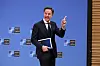 Mark Rutte med mappe i hånden gestikulerer foran blå NATO-bakvegg i Brussel.