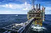 Kystvaktskip ved en olje- og gassplattform i Nordsjøen under blå himmel.