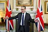 Keir Starmer gesturerer i et rom i 10 Downing Street med britiske flagg i bakgrunnen.