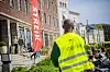Streikevakt i gul vest står foran hotellet Sommerro i Oslo med en rød streikefane.
