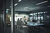 En kvinne presenterer for kolleger i et glassinnrammet kontor med bord og skjermer.