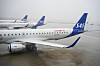 SAS-passasjerfly står på våt rullebane på Gardermoen med flere fly i bakgrunnen.