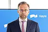 En mann i dress står foran en blå Høyre-bakgrunn under en pressekonferanse.