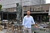 Tom Karp står ved bord og stoler på en uteservering foran en restaurant med statue av Winston Churchill.