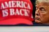 Donald Trump i profil i Det ovale kontor, med en rød «America is Back»-caps i forgrunnen.