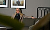 Forbundsleder i Norsk Sykepleierforbund sitter på en sofa i et rom med kunst på veggen.