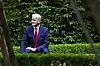 Statsminister Jonas Gahr Støre sitter utendørs foran grønne busker i Parkveien i Oslo.