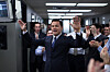 Leonardo DiCaprio som Jordan Belfort med armene hevet i et kontor omgitt av applauderende kolleger.