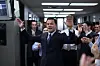 Leonardo DiCaprio som Jordan Belfort med armene hevet i et kontor omgitt av applauderende kolleger.