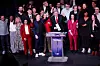 Flere LFI-politikere og aktivister står samlet på en scene foran et podium under et valgkampmøte i Paris.