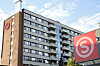 Studentboligbygg på Kringsjå i Oslo med stor rød logo på fasaden under blå himmel.