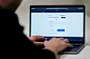 Hender skriver på en bærbar PC med ID-porten-innlogging på skjermen.