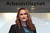 Ingvill Kvernmo står foran Arbeidstilsynets logo innendørs.