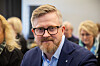 Mann i dress og briller sitter i forgrunnen på YS Inntektspolitisk konferanse 2023.