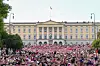 Stor menneskemengde foran Slottet i Oslo med norske flagg.