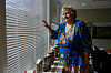 Erna Solberg i fargerik kjole ved et vindu under en forlagspresentasjon.