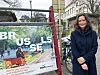Maria Varteressian står ved en fargerik Brussel-plakat i en bygate.