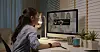 Kvinne ved hjemmekontor ser på en dataskjerm med videomøte og tegn til nettverksproblemer.