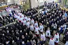 Sørgeprosesjon med prester i Oslo domkirke, omgitt av mange mennesker.