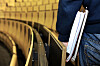 Student med notater under armen ved inngangen til et auditorium med gule seter.
