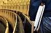 Student med notater under armen ved inngangen til et auditorium med gule seter.