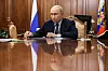 Vladimir Putin sitter ved et blankpolert skrivebord i et trepanelt rom med russiske flagg.