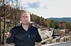 Kjetil Wetterstad Jensen, i uniform foran brannskadde bygningsrester med skog og ås i bakgrunnen.