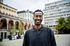Fawzi Warsame står foran historiske bygninger og et moderne kontorbygg i Oslo sentrum.
