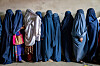 En rekke afghanske kvinner i blå og svarte burkaer står samlet og venter i Kabul.