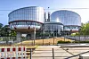 Moderne glassbygninger ved Det europeiske menneskerettsdomstolen i Strasbourg, sett fra en avsperret gangvei.