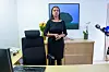 Kamzy Gunaratnam står i et kontor med skrivebord, stol, skap og planter.