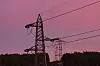 Flere strømmaster står mot en rosa himmel over en mørk skog i Oslo.