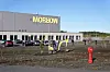 Morrow-fabrikken i Arendal med skilt på fasaden, anleggsområde og rød brannhydrant i forgrunnen.