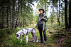 Hans Rustad står på en skogssti med en flekket hund i forgrunnen.