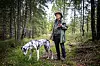 Hans Rustad står på en skogssti med en flekket hund i forgrunnen.