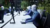 Humanoide roboter sitter ved datamaskiner i et lyst, moderne kontor.