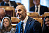 Mahmoud Farahmand i dress smiler under spørretimen i Stortinget, med andre politikere i bakgrunnen.