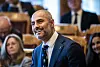 Mahmoud Farahmand i dress smiler under spørretimen i Stortinget, med andre politikere i bakgrunnen.