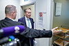 Børge Brende står ved en dør mens pressefotografer og en annen person er i forgrunnen.
