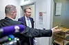 Børge Brende står ved en dør mens pressefotografer og en annen person er i forgrunnen.