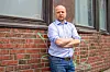 Trygve Slagsvold Vedum står med korslagte armer foran en teglsteinsvegg på Tøyen.