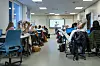 Lærer underviser foran tavlen mens elever sitter ved pulter i et lyst klasserom.