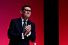 Andy Burnham applauderer foran en rød bakgrunn på Labour-partiets konferanse.