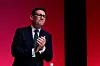 Andy Burnham applauderer foran en rød bakgrunn på Labour-partiets konferanse.