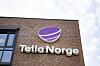 Telia Norge-logo på en teglsteinsbygning mot lys himmel.