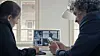 To kolleger samarbeider ved et bord med videomøte på en bærbar datamaskin.