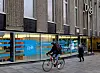 Syklist passerer en DNB-filial i Stavanger, med en fotgjenger utenfor.