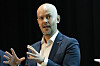 John-Eivind Velure gestikulerer under en panelsamtale på en mørk scene.