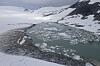 Isflak i et smeltevannsbasseng omgitt av snødekte fjellsider ved Harbardsbreen.